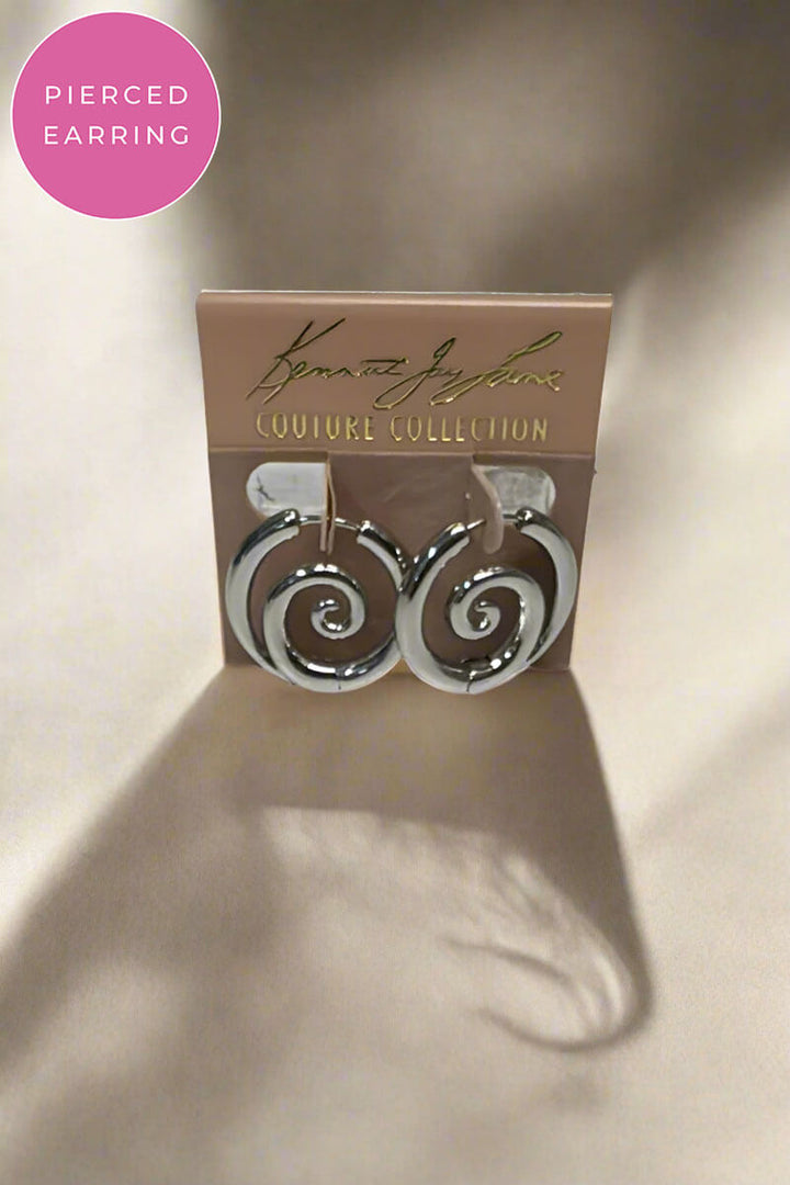 A pair of silver spiral hoop earrings displayed on a tan jewelry card labeled 'Kenneth Jay Lane Couture Collection.' A pink circular badge in the top left says 'Pierced Earring.